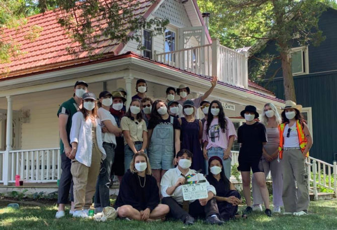 'Little Bird' cast and crew wearing protective masks standing before a house on set