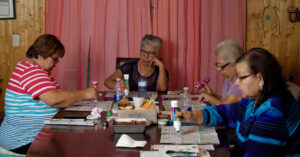 Screen capture from Radio Bingo documentary, depicting four women playing bingo at dining room table. 