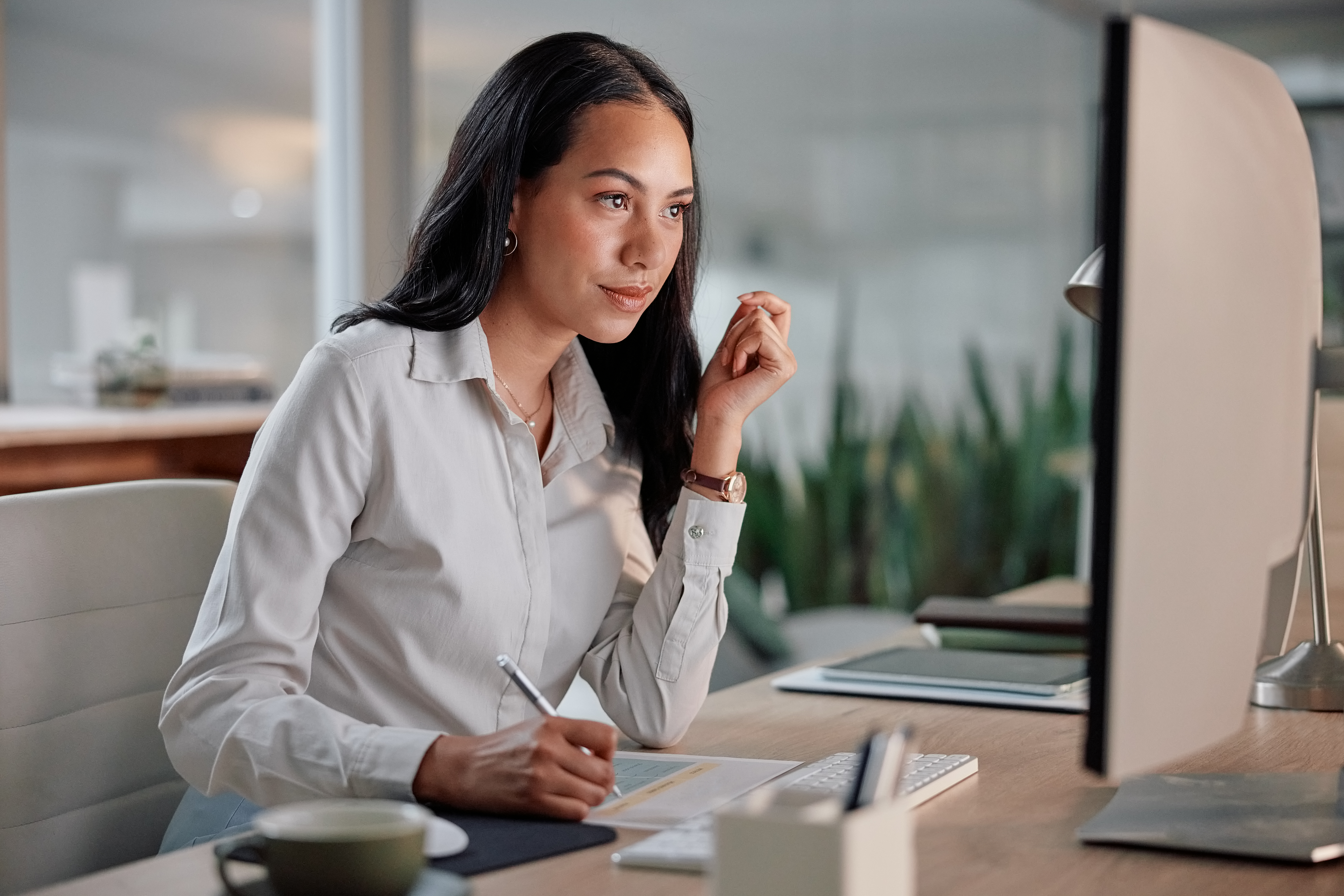 Woman at desk in office, writing a creative brief.